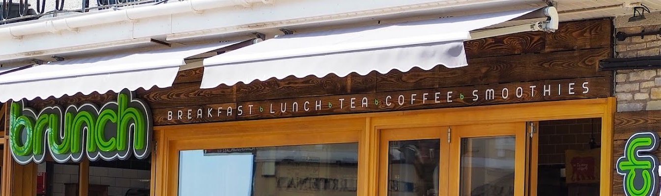 The Brunch shopfront: a green ‘brunch’ sign, white awnings and a wooden fascia reading Breakfast, Lunch, Tea, Coffee, Smoothies above golden window frames